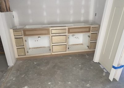 Partially installed bathroom vanity cabinets without sinks or countertops in a room under construction.