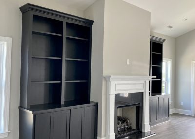 Bright room with dark built-in shelves and a white fireplace on a light wood floor.