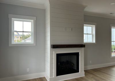 Modern living room with a central shiplap fireplace, wood mantel, and two windows on either side.