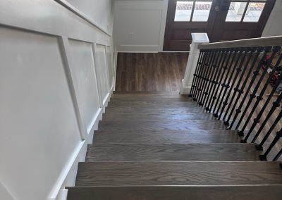 View from the top of a wooden staircase leading to a foyer with double doors and wood flooring.