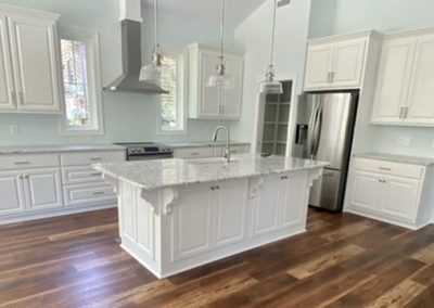 Bright kitchen with white cabinets, granite countertops, stainless steel appliances, and wood flooring.