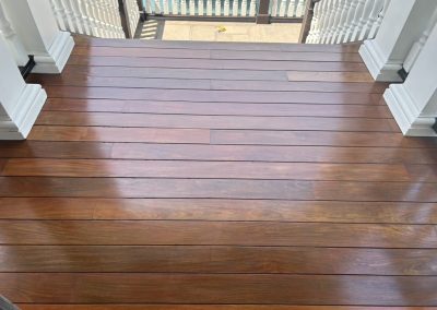 Polished wooden stairs with white railings leading down to a patio overlooking water.