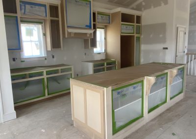 Kitchen under construction with cabinets and island covered and protected by paper and painter’s tape.