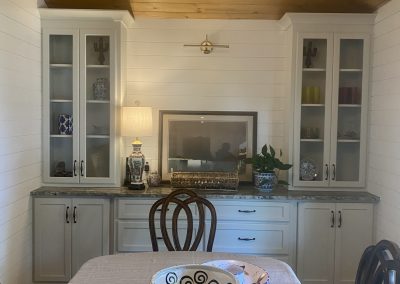 Dining room with a wooden ceiling, cabinets, a table with bowls, and a chandelier overhead.