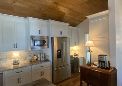 A cozy kitchen with white cabinets, a stainless fridge, and warm lighting from two table lamps.