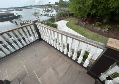 View from a balcony overlooking a landscaped yard, stone pathway, and waterfront with docks.