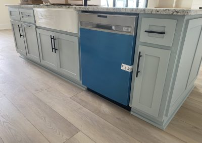 A kitchen island with light blue cabinets and a dishwasher covered with blue protective film.